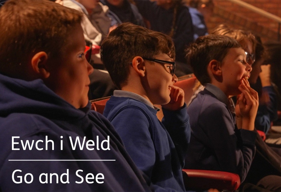 Three boys sat in an audience enjoying a production on stage